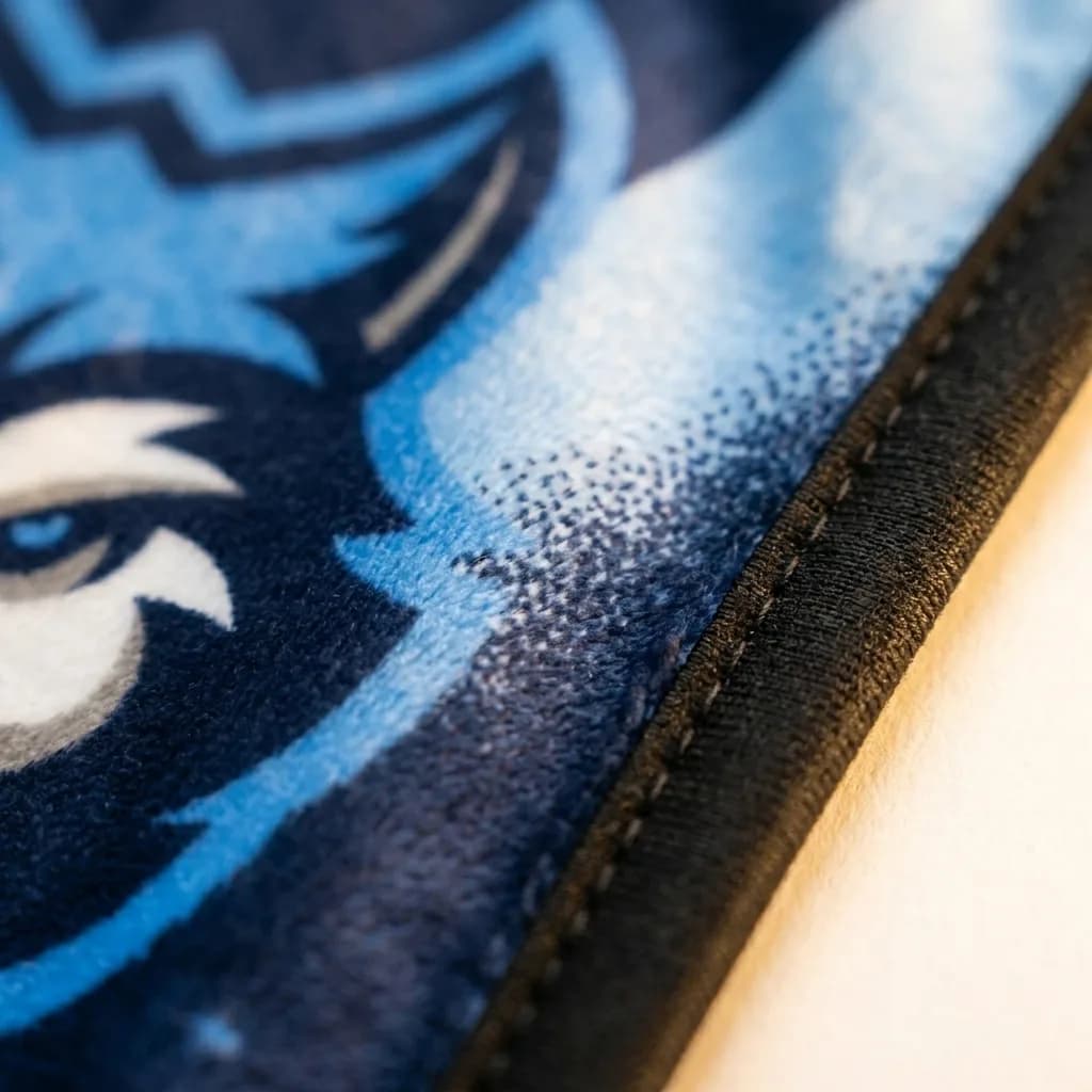 Macro close-up of a printed mascot design and stitched edge binding on NubaySoft fabric