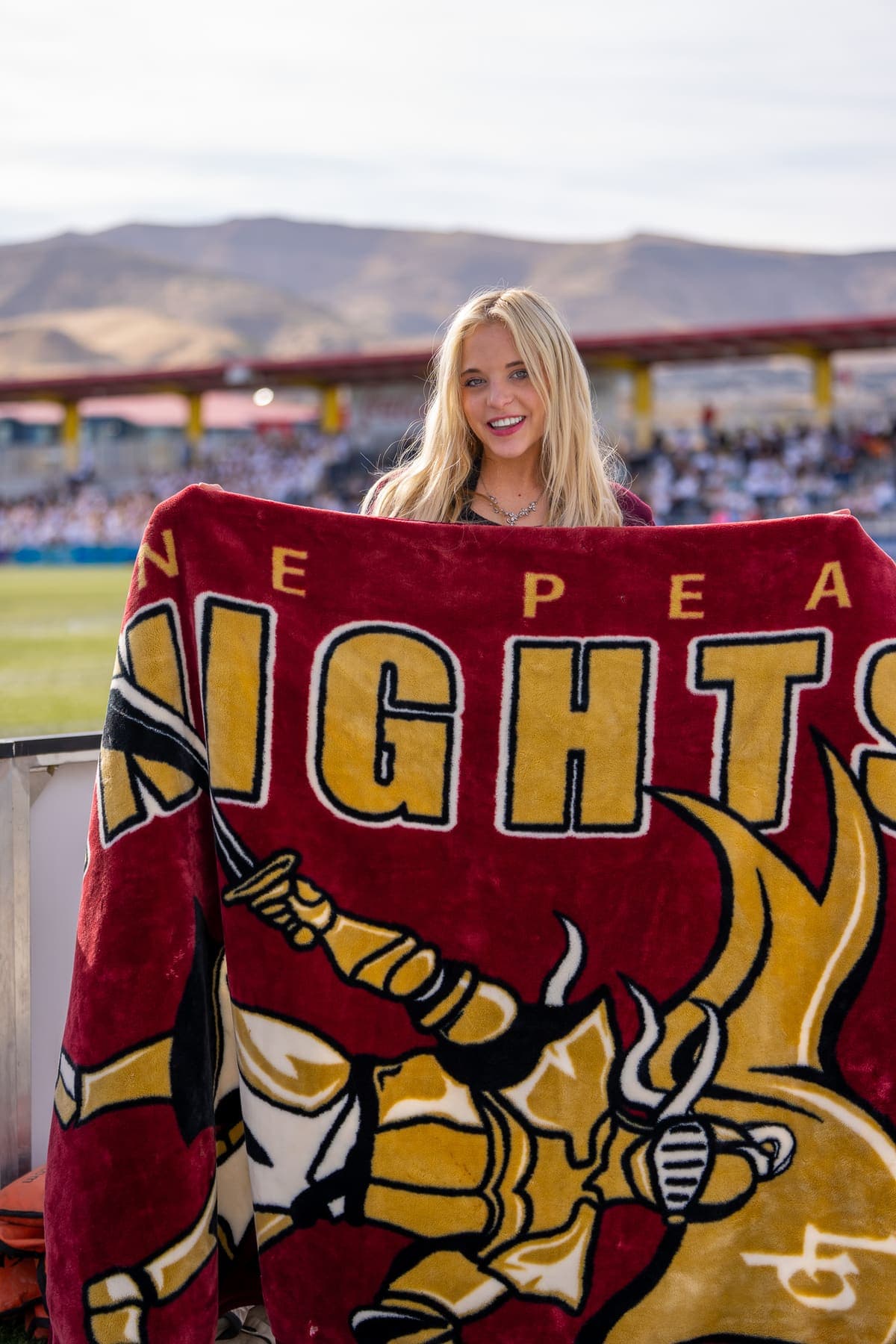 Student at a stadium holding up a heavyweight custom printed Knights keepsake blanket