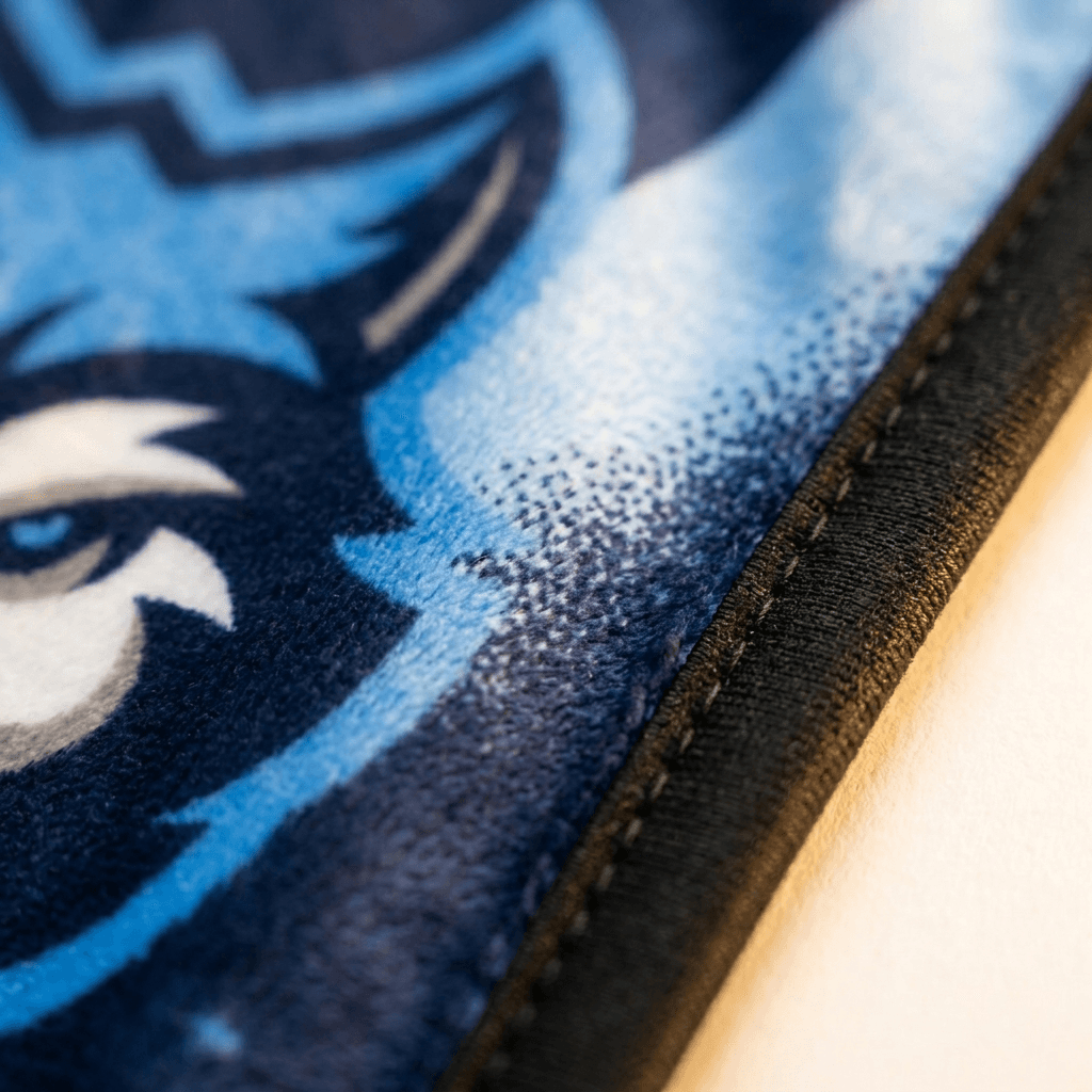 Macro close-up of a printed mascot design and stitched edge binding on NubaySoft fabric